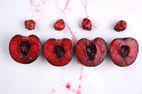 1604607-343760-image-of-fresh-cherries-cut-in-halves-with-seeds-and-cherry-juice-on-white