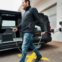 A man walking a dog in front of a black van