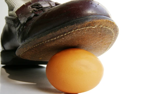 Closeup of a business man's shoe about to step on an egg